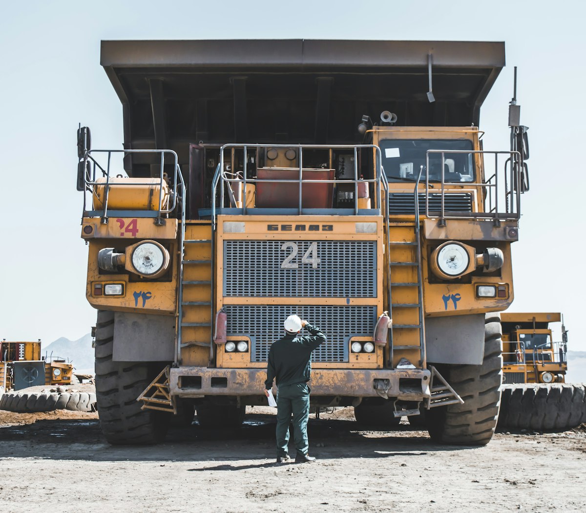 Worker standing beside a large yellow haul truck